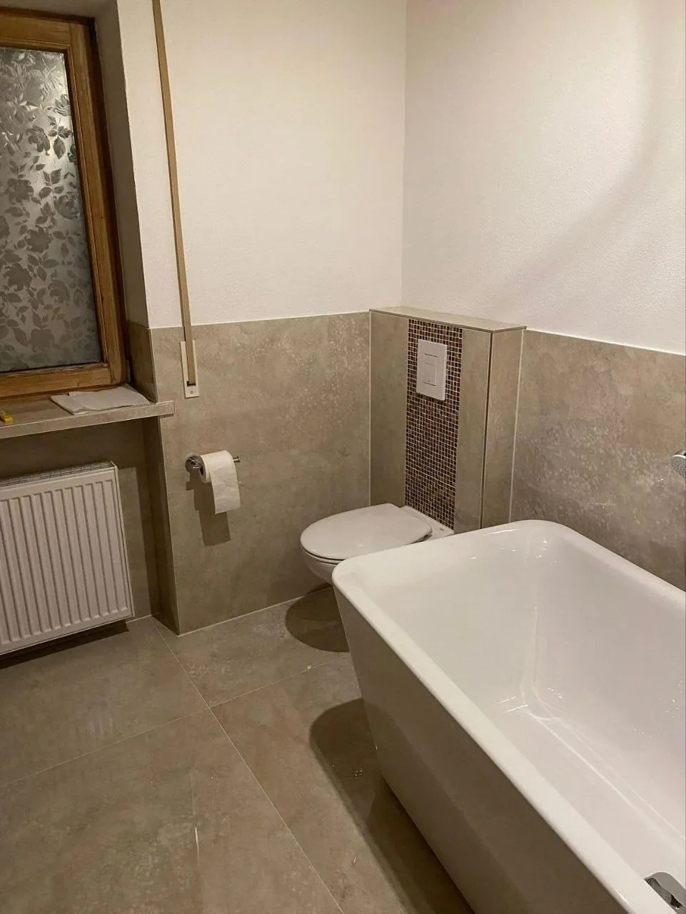 Fertiges Badezimmer mit eingelassener Badewanne und beigen Wandfliesen