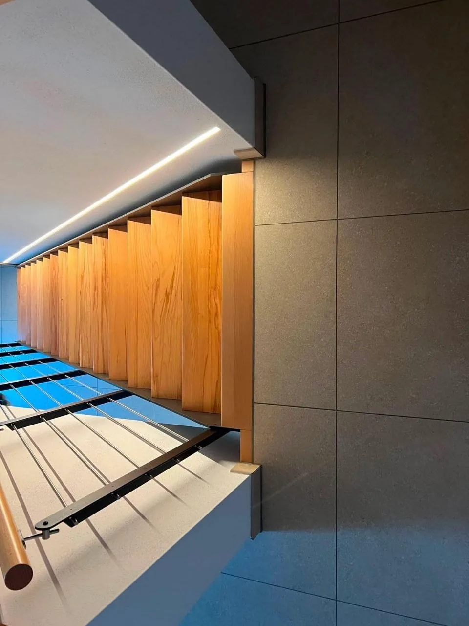 Bad-Detail mit Holzelement, grauen Großformatfliesen und LED-Beleuchtung