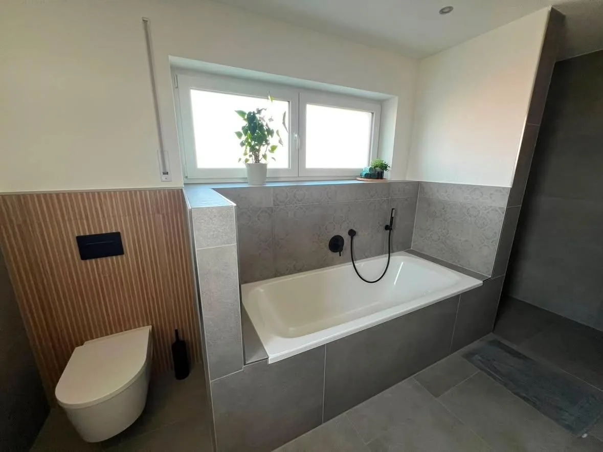 Badezimmer mit eingelassener Badewanne und Wand-WC