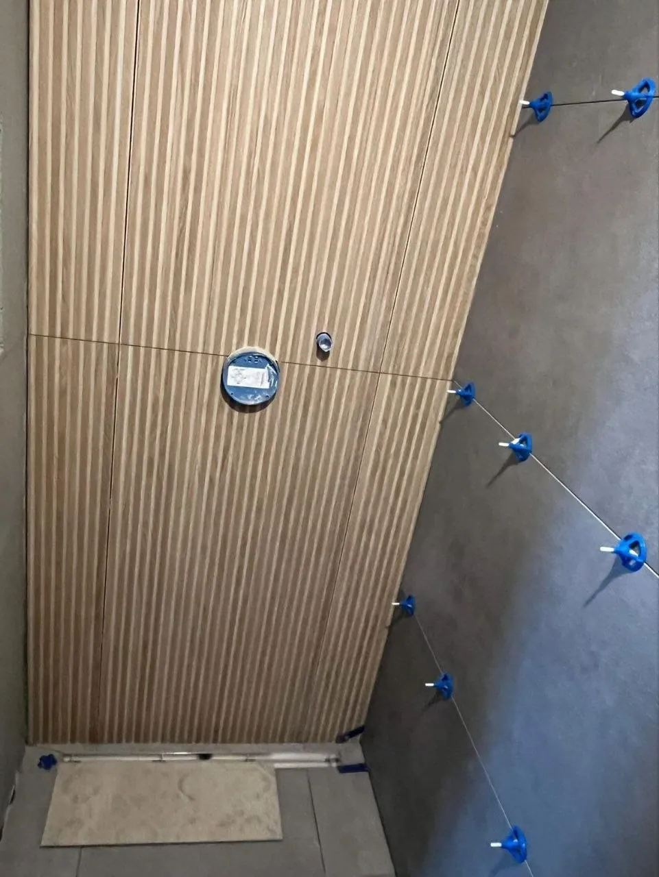 Bodengleiche Dusche mit beigen Strukturfliesen und Linienablauf im Bau
